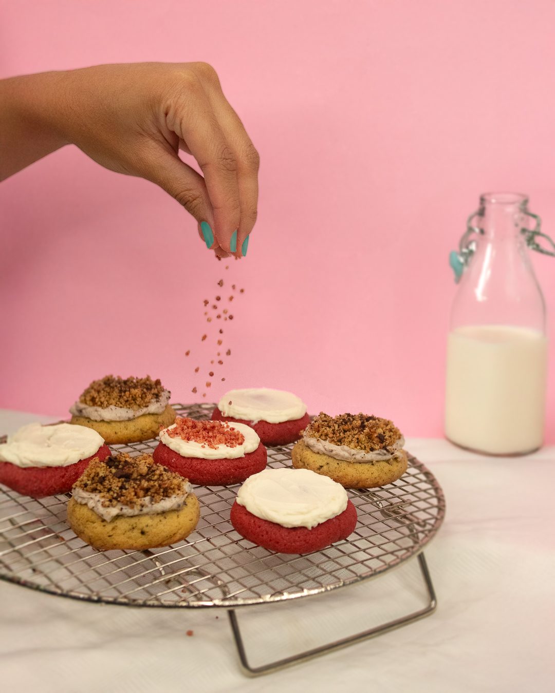 Una mano espolvorea crumble sobre galletas recién decoradas